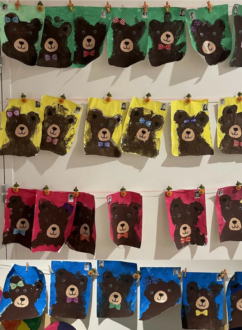 Des portraits d'oursons peints par les élèves de petite section, alignés sur un mur.