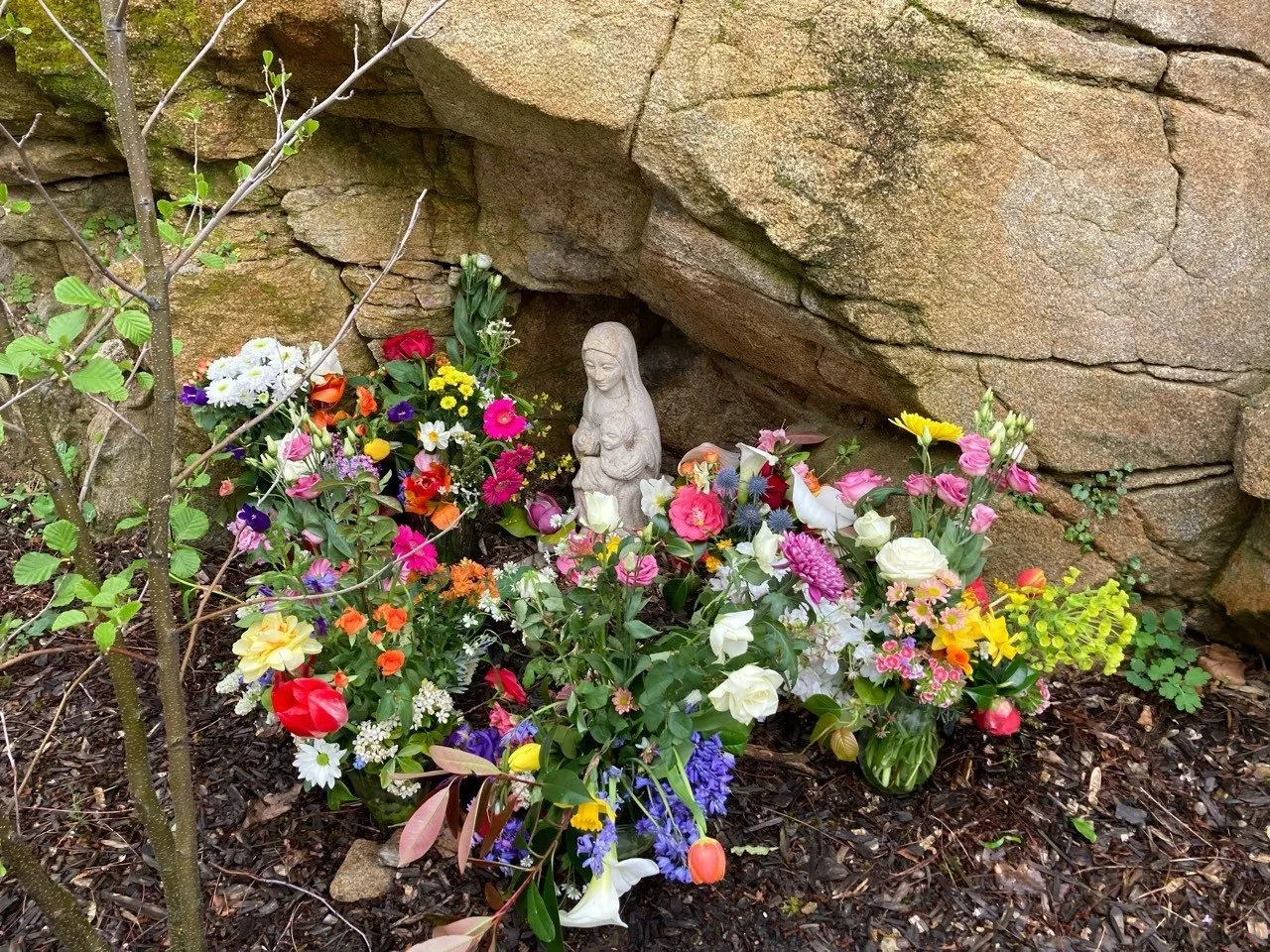 La statue de la Vierge de la cour élémentaire, entourée des bouquets apportés par les classes.