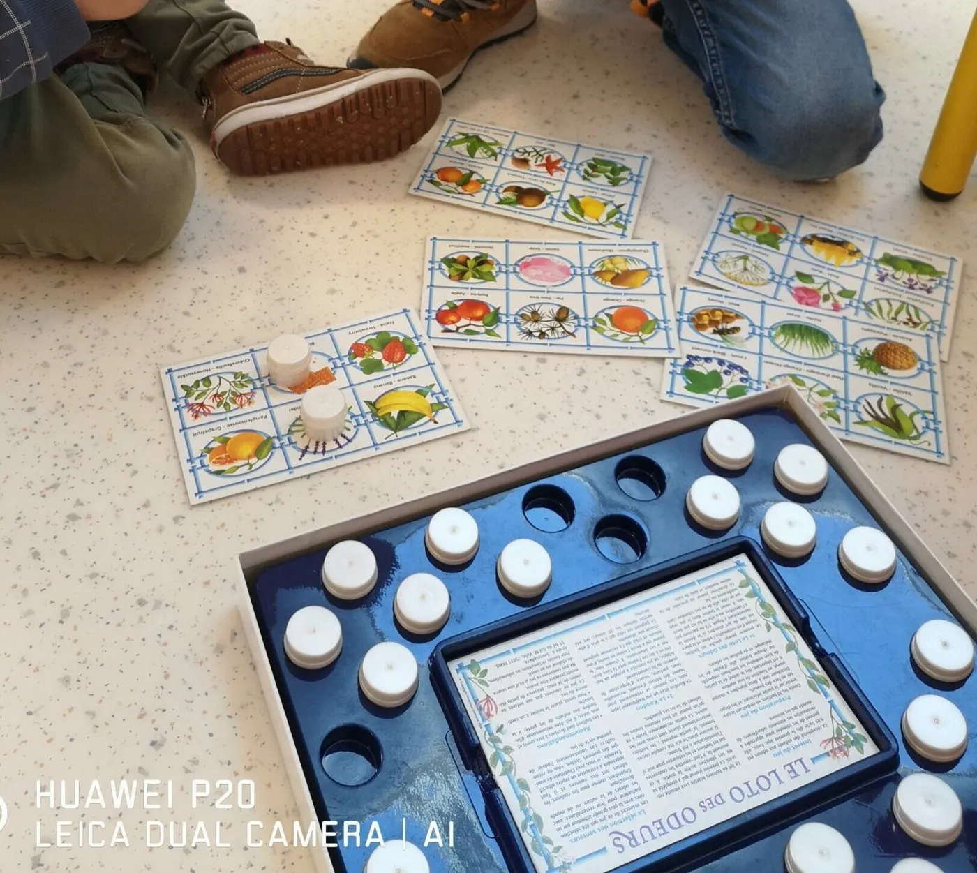 Un jeu de société posé au sol, au milieu des cartes, pendant une partie entre élèves.