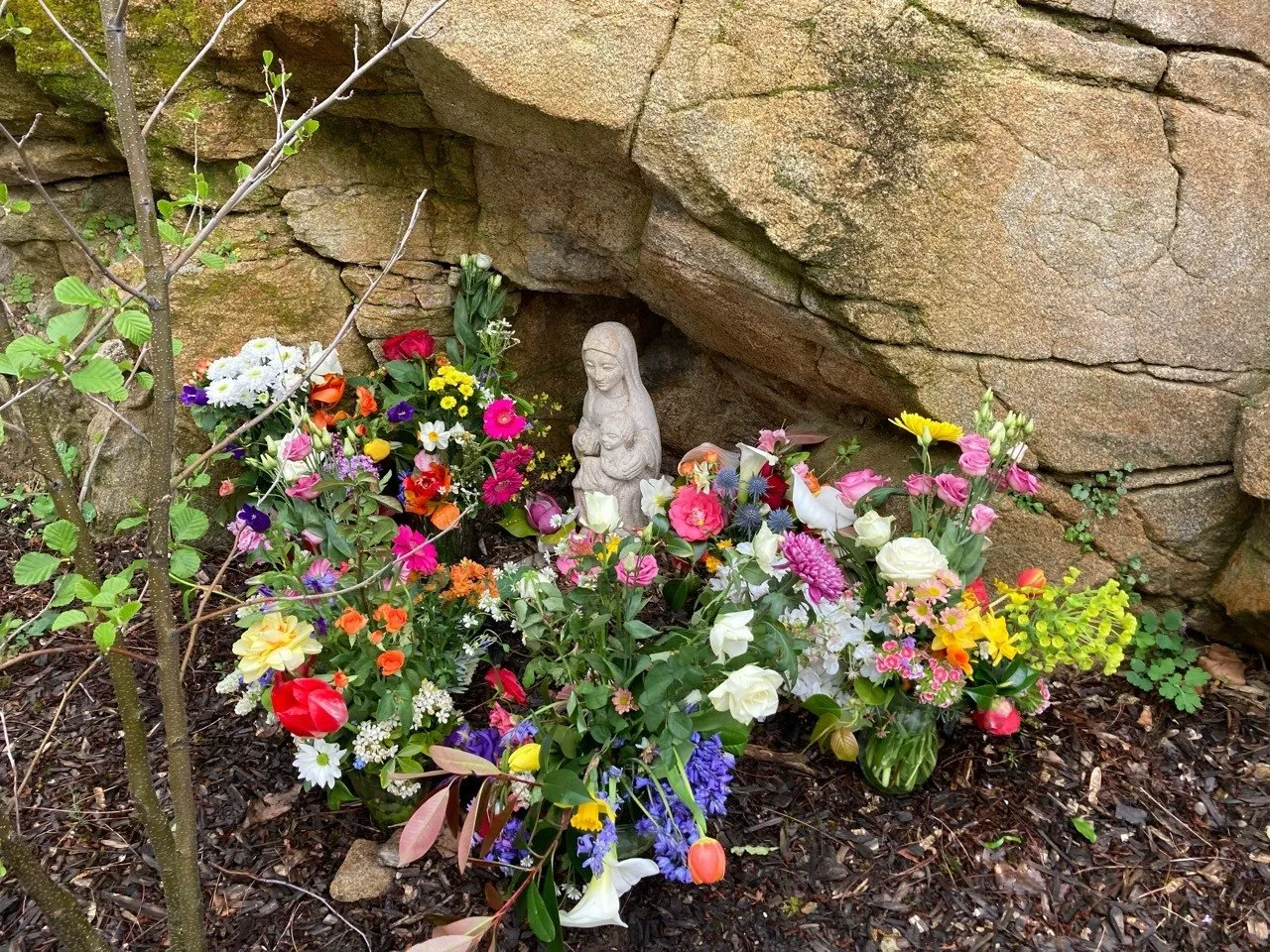 La statue de la Vierge de la cour élémentaire, entourée des bouquets apportés par les classes.