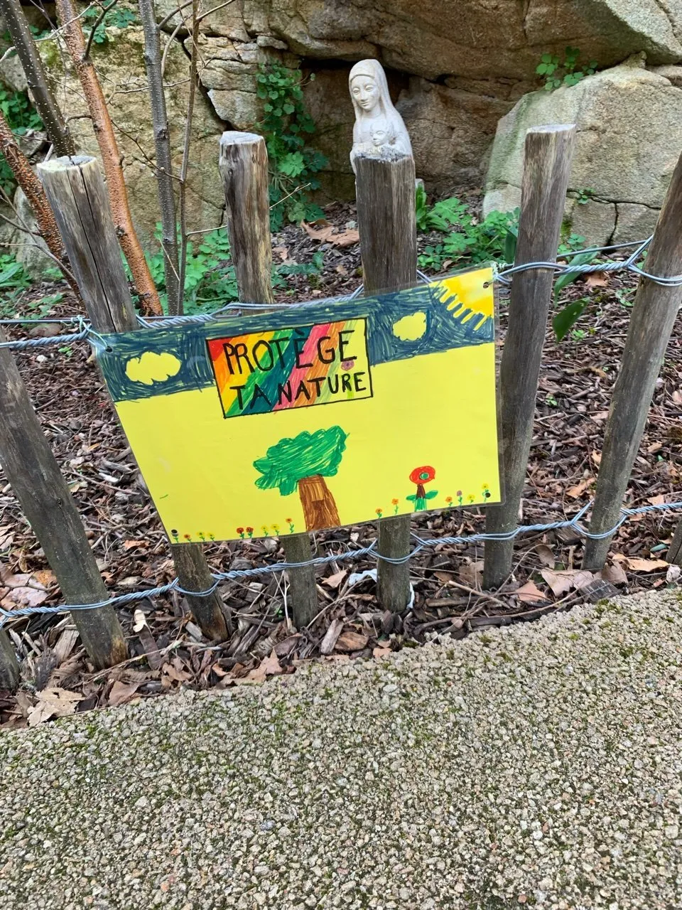 Une affiche peinte par les élèves, accrochée à une clôture de la cour : « Protège ta nature ! ».